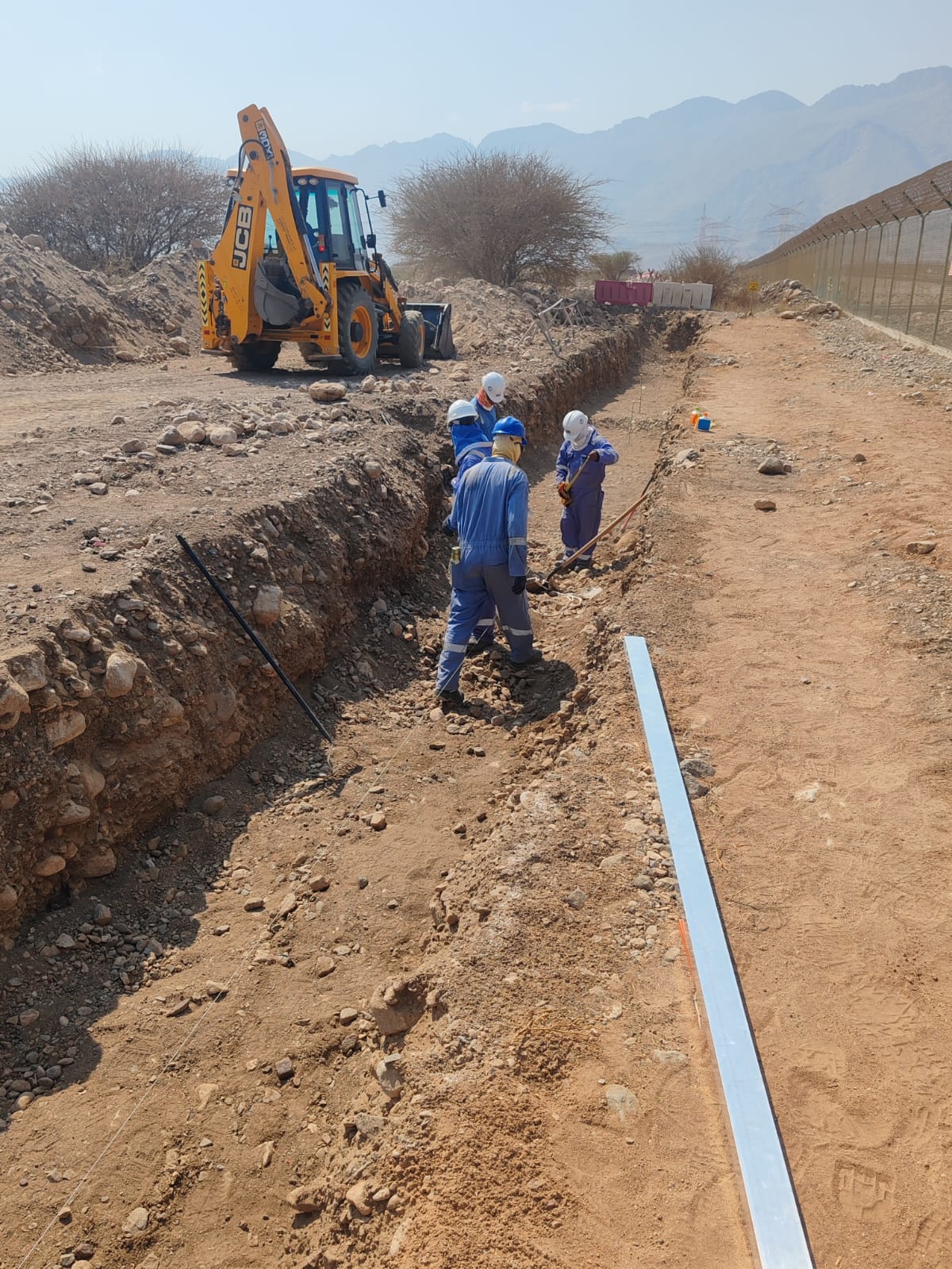 Road construction and re-sheeting work in desert terrain.